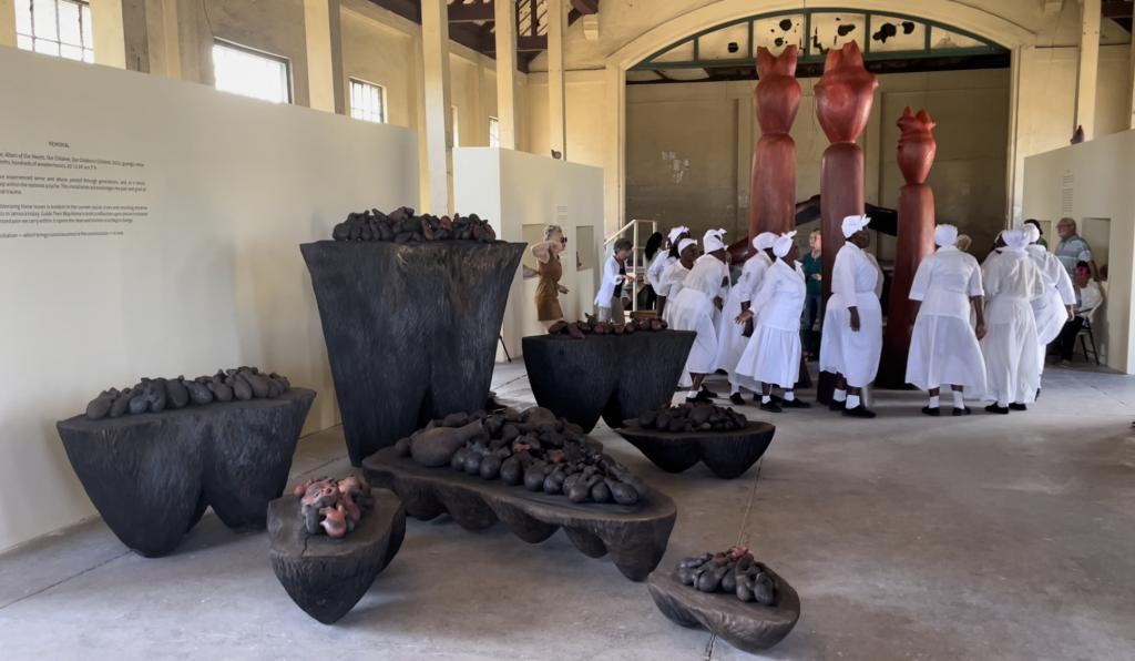 Part of GUIDE THEIR WAY HOME, Alters of our Hearts, Our Children, Our Children&#039;s Children, 2021, 7 plinths, hundreds of hand carved hearts, mahogany, cedar, guango, 20x15&#039;; The St Ann Senior Citizens Cultural Group sanctifying art work